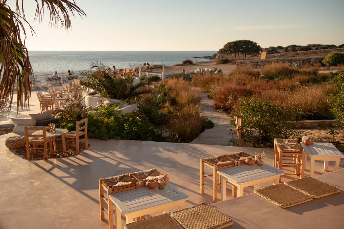 Sunset Antiparos | Restaurant in Antiparos, Greece | Photograph of restaurant tables in foreground and foliage/ocean in the background